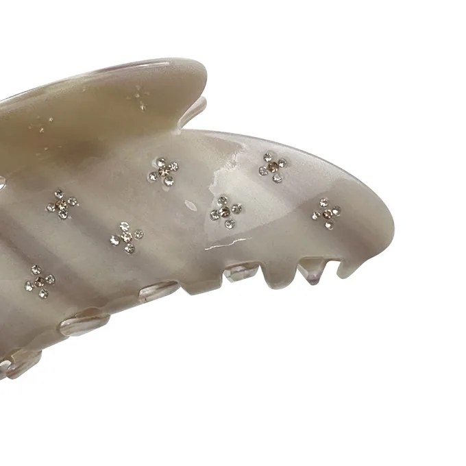Hand-set rhinestone flowers drilled into a pearl acetate shark claw clip