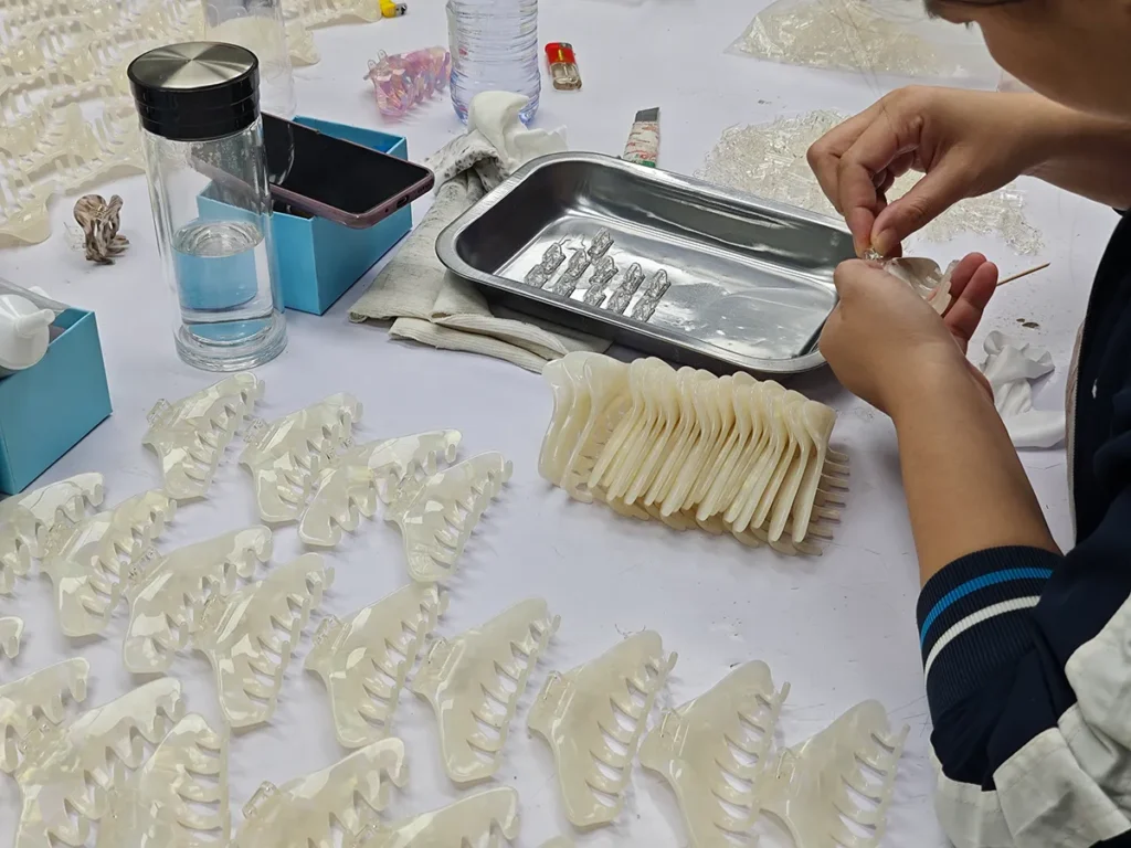 Worker hand-assembling acetate claw clip components