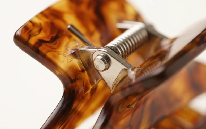 Close-up of the steel spring bar and hinge pin fitted into the body of a tortoiseshell acetate hair claw clip