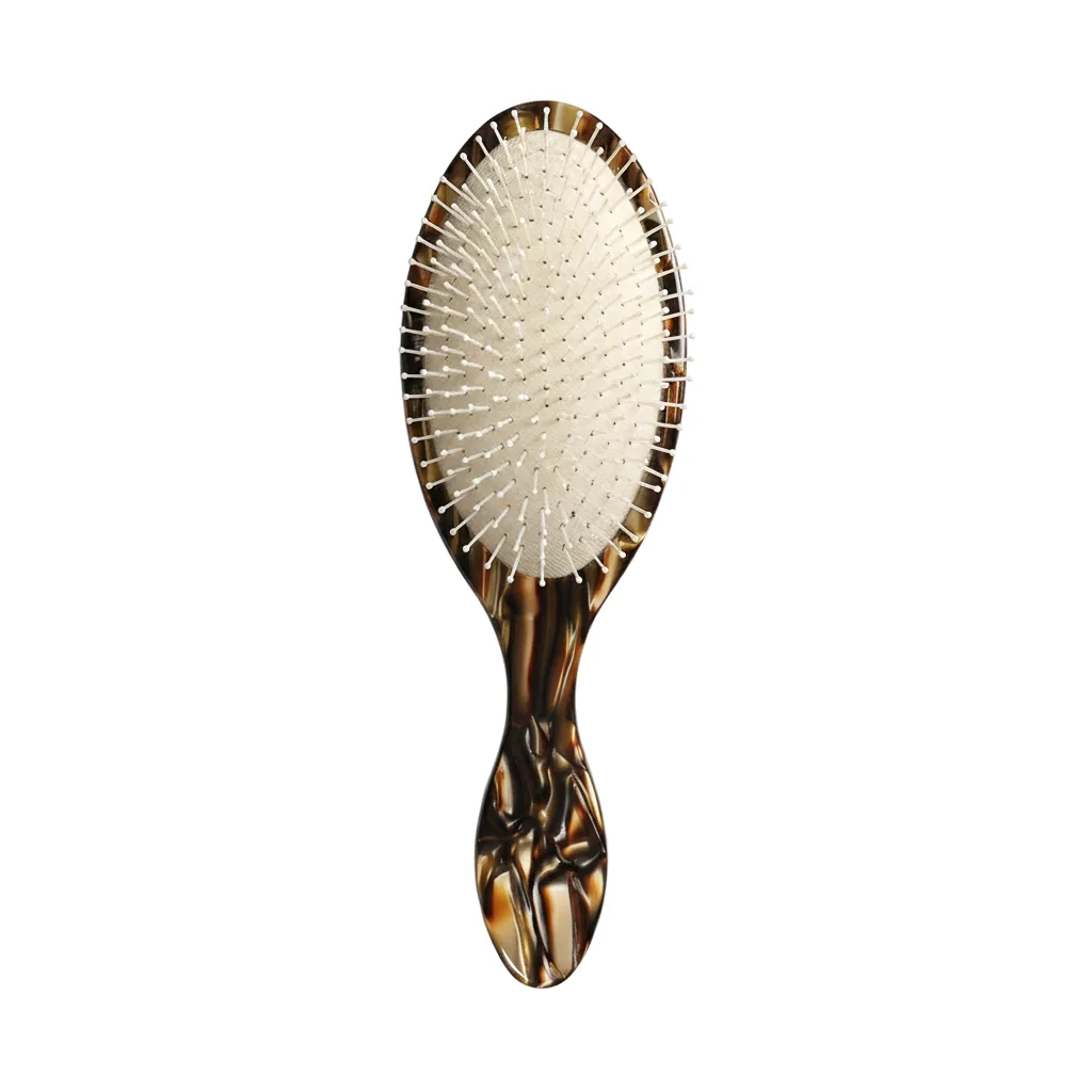 Gold tortoiseshell acetate oval cushion brush standing upright, front view showing the cream cushion pad and white ball-tip pins