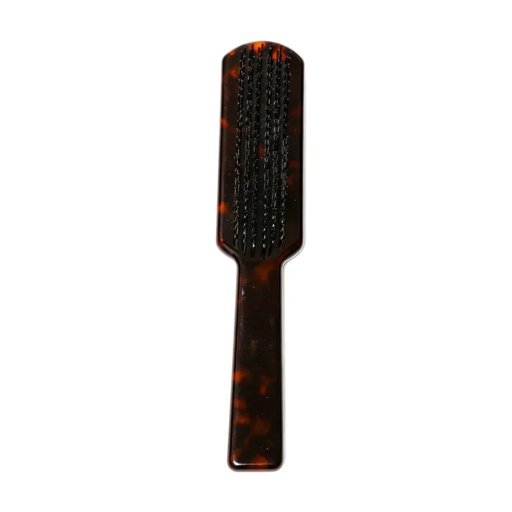 Tortoiseshell cellulose acetate paddle brush standing upright, showing seven rows of ball-tip nylon pins set straight into the solid acetate body