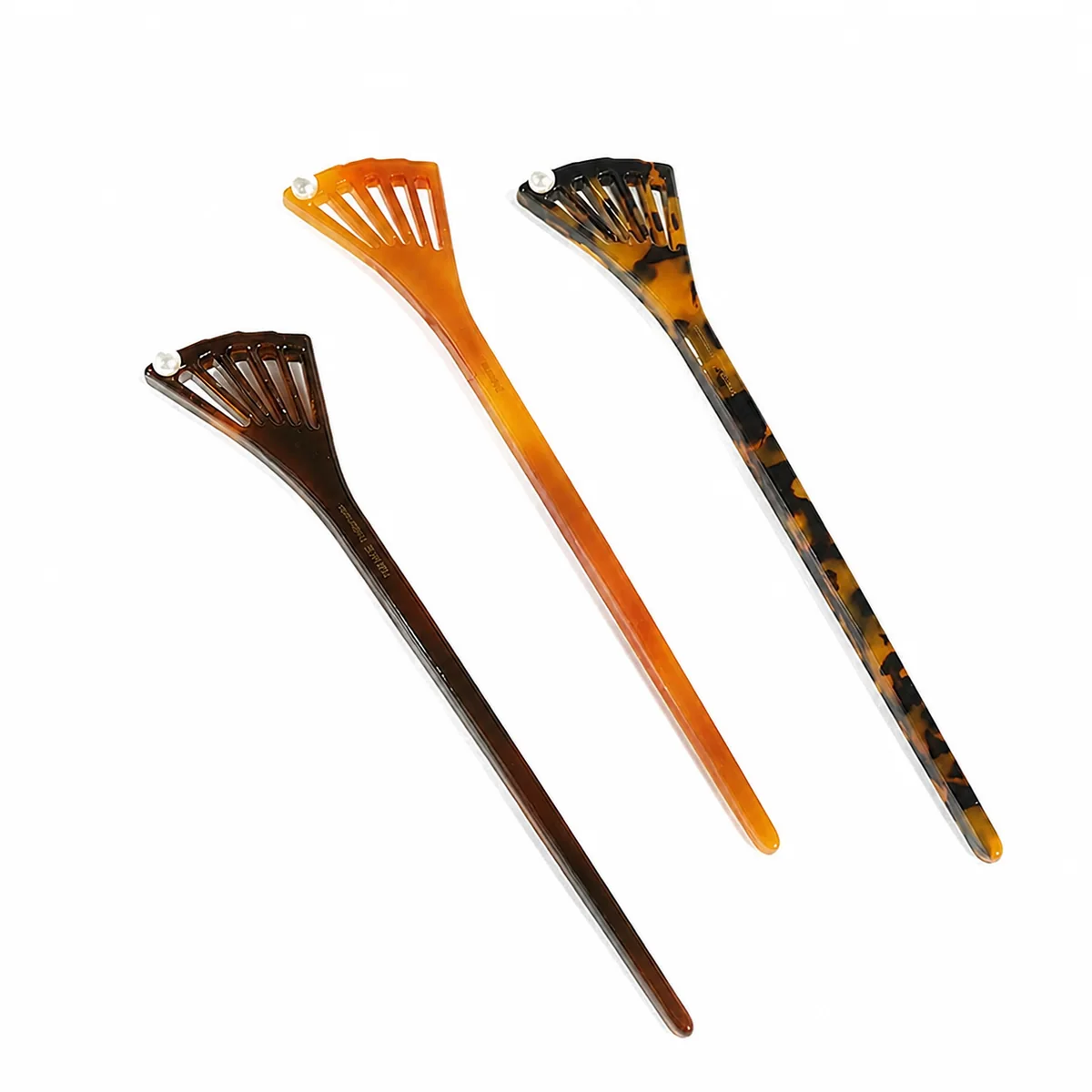 Four fishtail acetate hair sticks fanned out in dark brown, amber and tortoiseshell