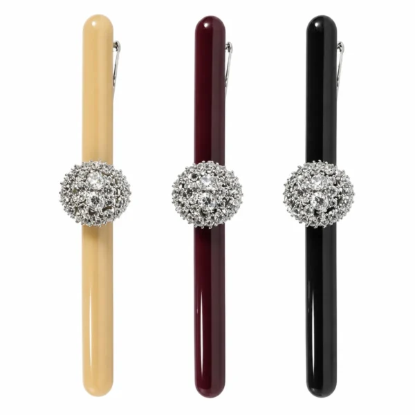 Three 8.5 cm slim acetate bar barrettes standing upright on white, each with a single pave crystal ball set at the centre, in beige, wine and black