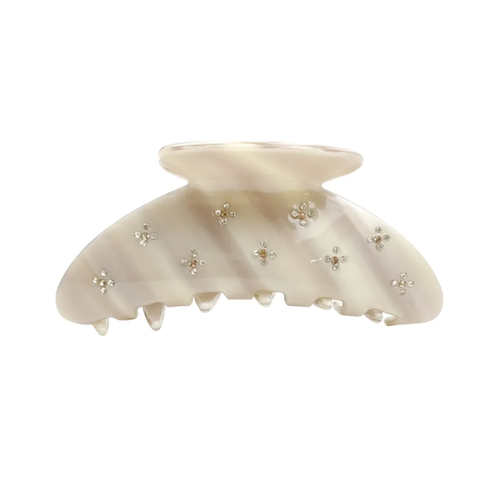Pearl acetate shark claw clip on a white background with hand-set rhinestones scattered across the shell