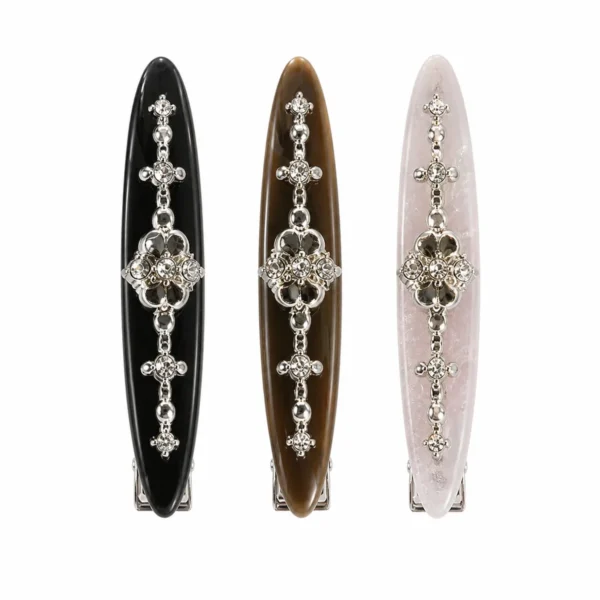 Three 7.5 cm willow-leaf acetate barrettes standing upright on white with an antique-silver crystal motif set into the face, in black, brown and pale pink