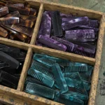 A divided wooden workshop tray filled with short handle-free acetate pocket combs in tortoiseshell, purple marble, black and teal