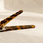 Tortoiseshell acetate duckbill clip lying open, showing the long flat jaw and the hinge