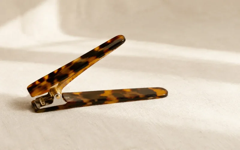 Tortoiseshell acetate duckbill clip lying open, showing the long flat jaw and the hinge