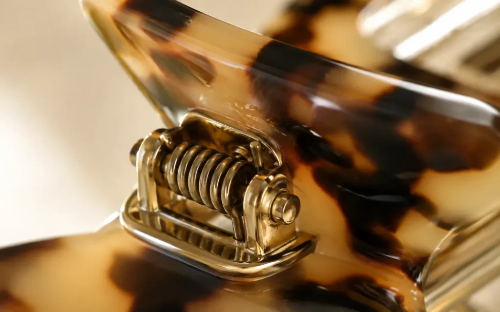 Macro view of the coil spring and gold-tone metal base of an acetate hair clip