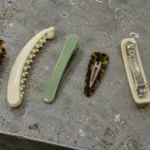 One of each type of acetate hair clip on a workbench: claw, banana, duckbill, snap, French barrette turned over, and side clip