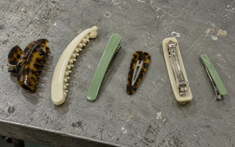 One of each type of acetate hair clip on a workbench: claw, banana, duckbill, snap, French barrette turned over, and side clip