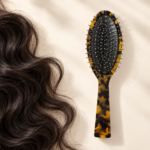 Rounded steel-pin cushion brush beside a section of thick dark hair